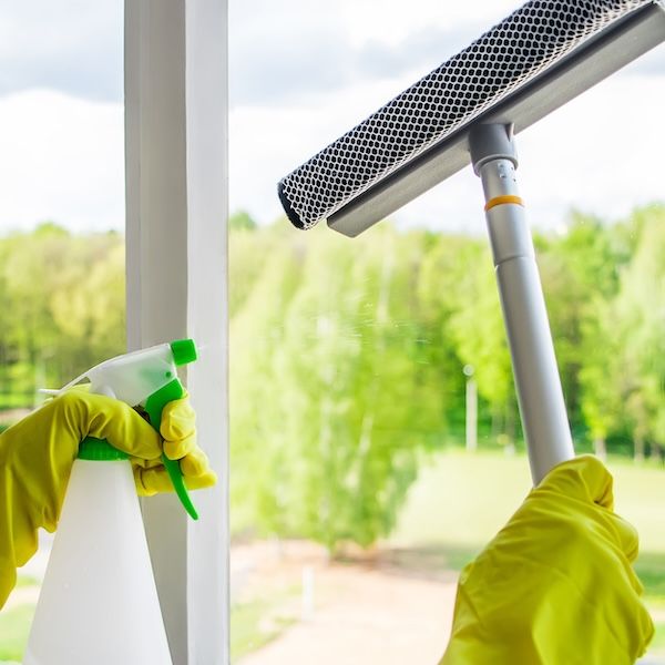 Window washing and home cleaning. Housekeeper in gloves washes and wipes dirty glass.